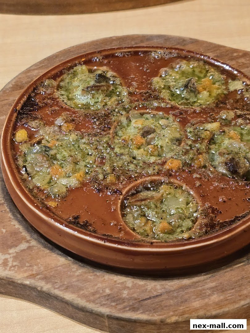 A close-up shot of escargots in garlic butter and herbs, served in a traditional brown ceramic dish.