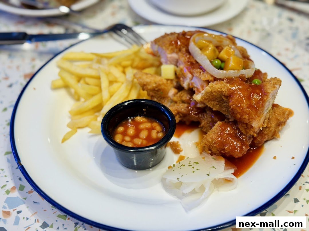 A plate of crispy fried chicken with fries, baked beans, and pickled onions.