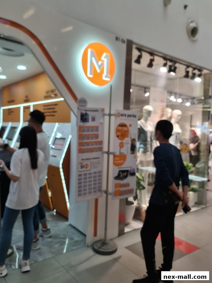 A bright M1 NEX phone shop with a prominent orange logo and displays inside.
