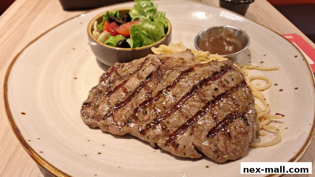 A juicy grilled steak served with pasta and a side salad.