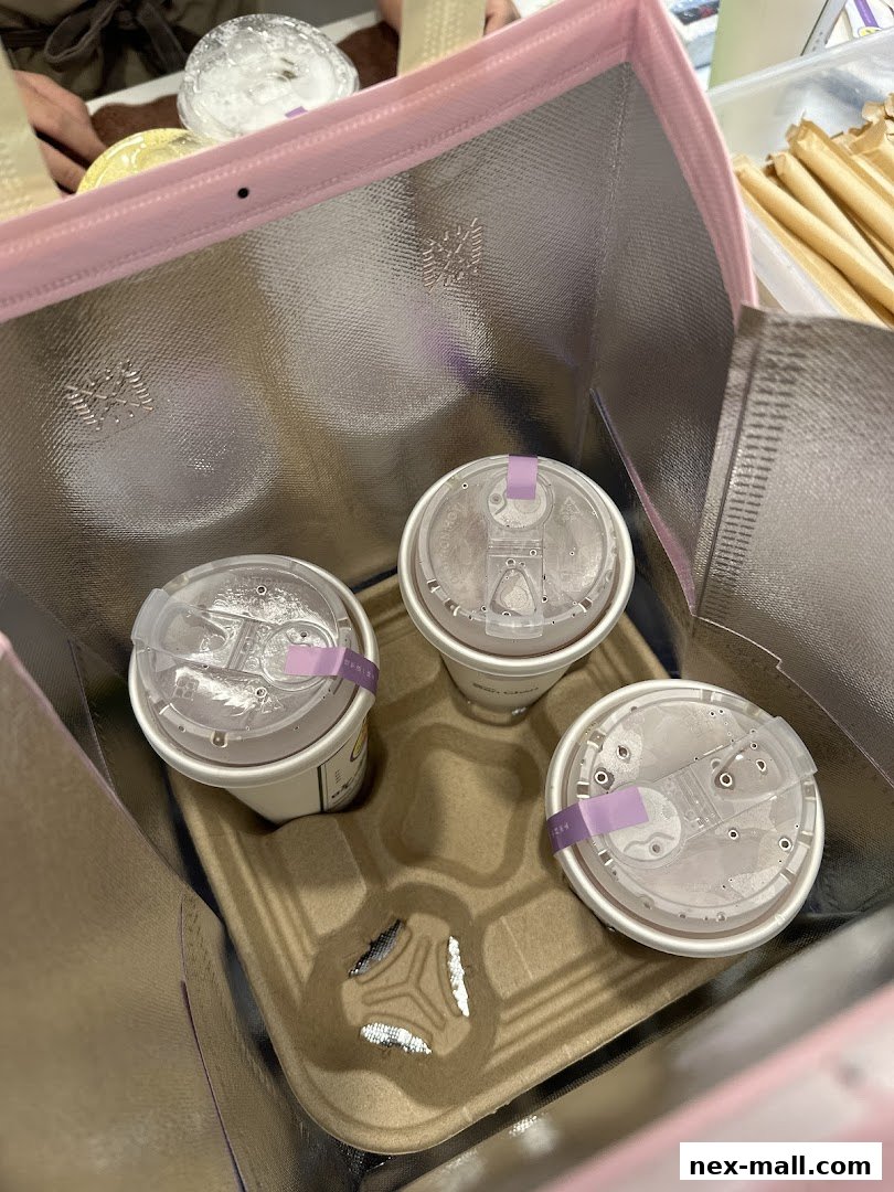 Three cups of bubble tea are neatly arranged in a thermal bag with straws in the background.