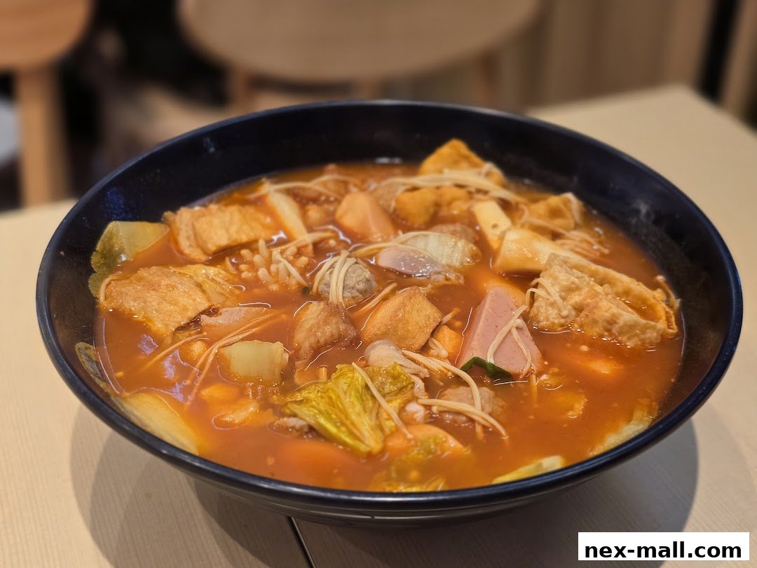 A steaming bowl of Mala Tang filled with various ingredients in a rich, orange broth.