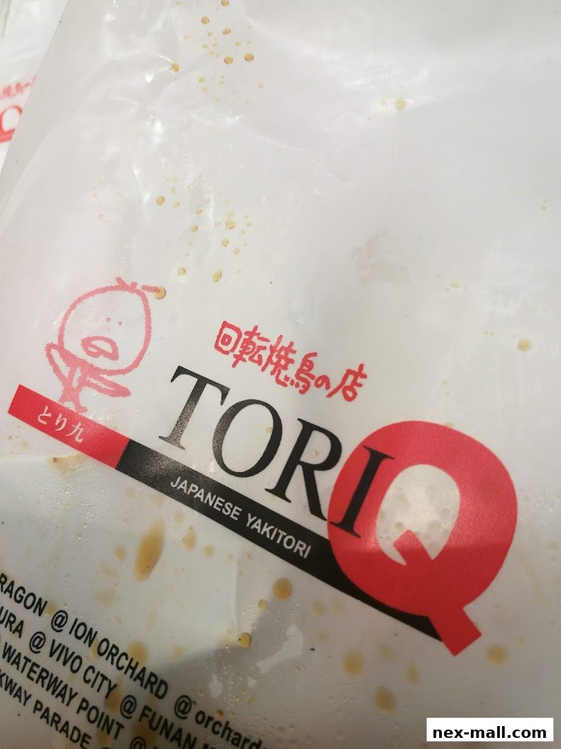 A close-up of a TORI-Q Japanese Yakitori paper bag with a cartoon character and store locations.