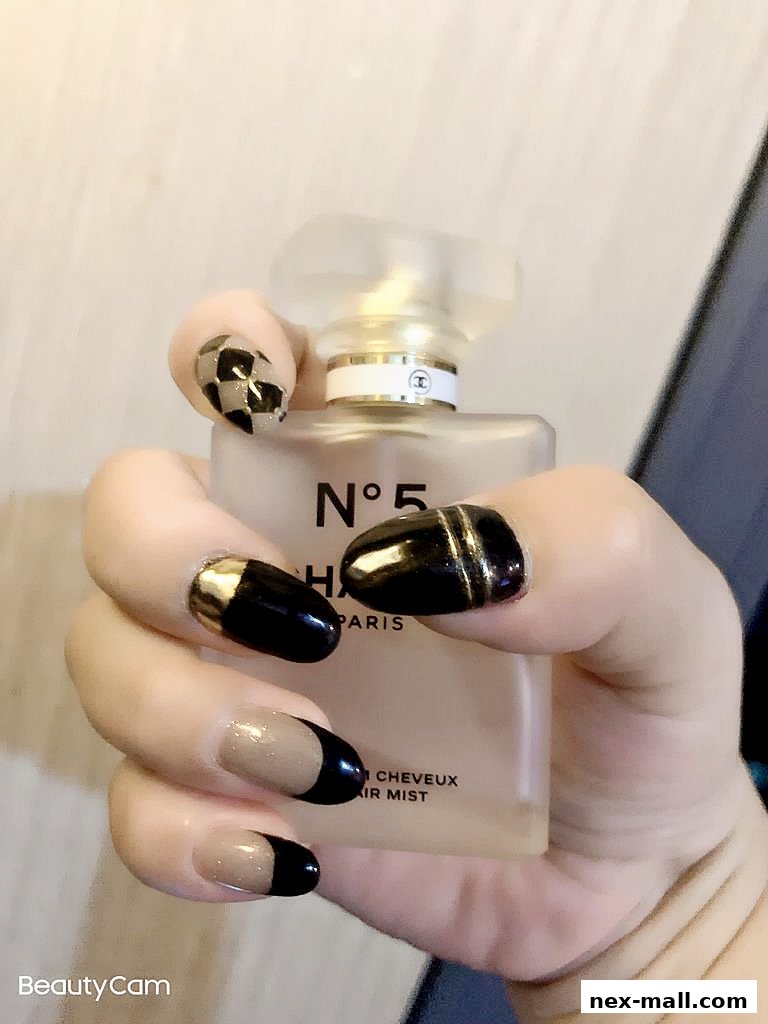A hand with stylish black and gold nails holds a Chanel No. 5 hair mist.