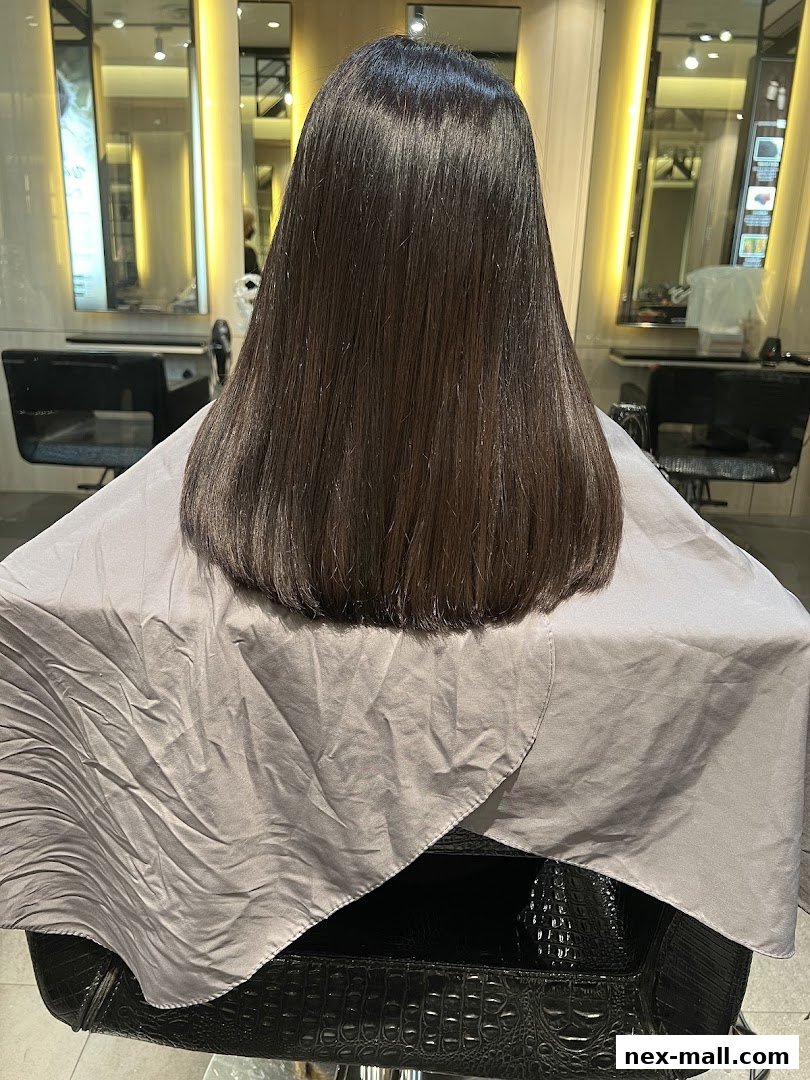 A person's back with long, dark, freshly styled hair in a salon.