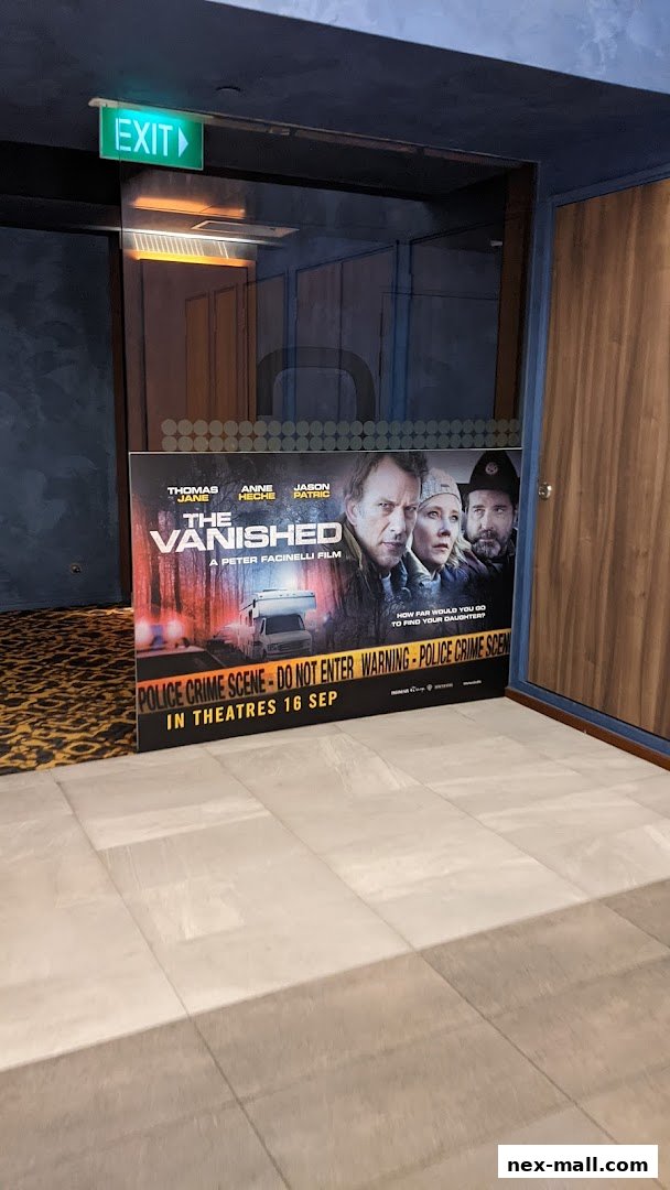 A movie poster for 'The Vanished' is displayed in front of a glass door with an exit sign.