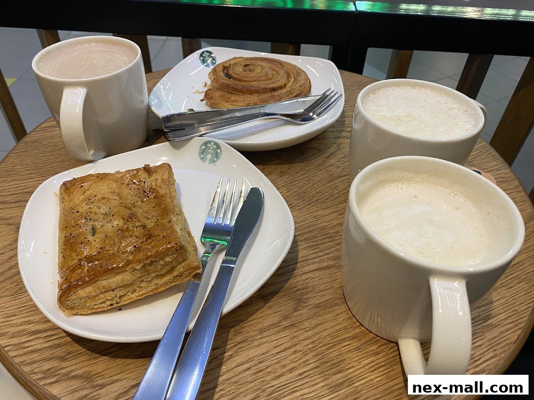 A table with three cups of coffee and two pastries from Starbucks.