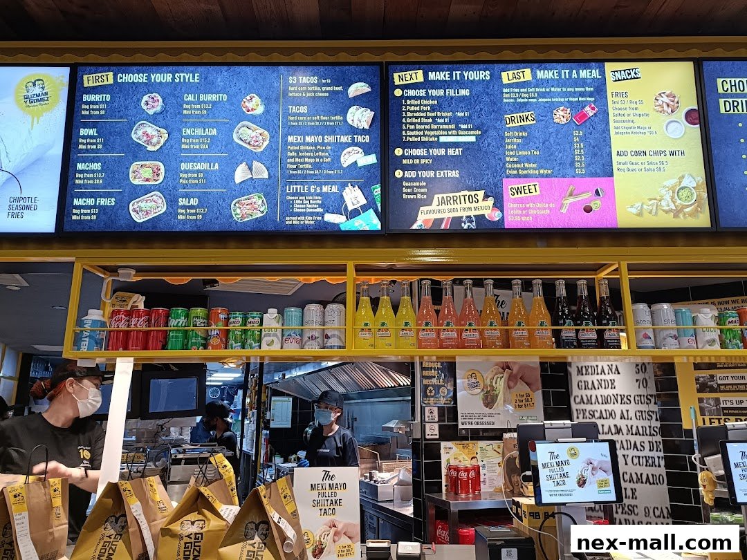 A digital menu board displays various Mexican food options and drinks at Guzman y Gomez.