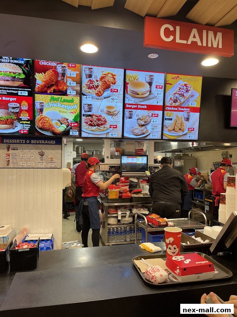 A Jollibee restaurant counter with digital menus displaying food items and prices.