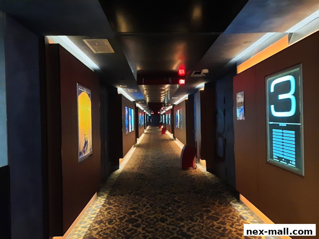 A dimly lit cinema hallway with movie posters and illuminated room numbers.