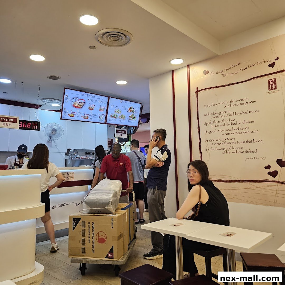 Customers at Ya Kun Kaya Toast, with digital menus and a wall poem.