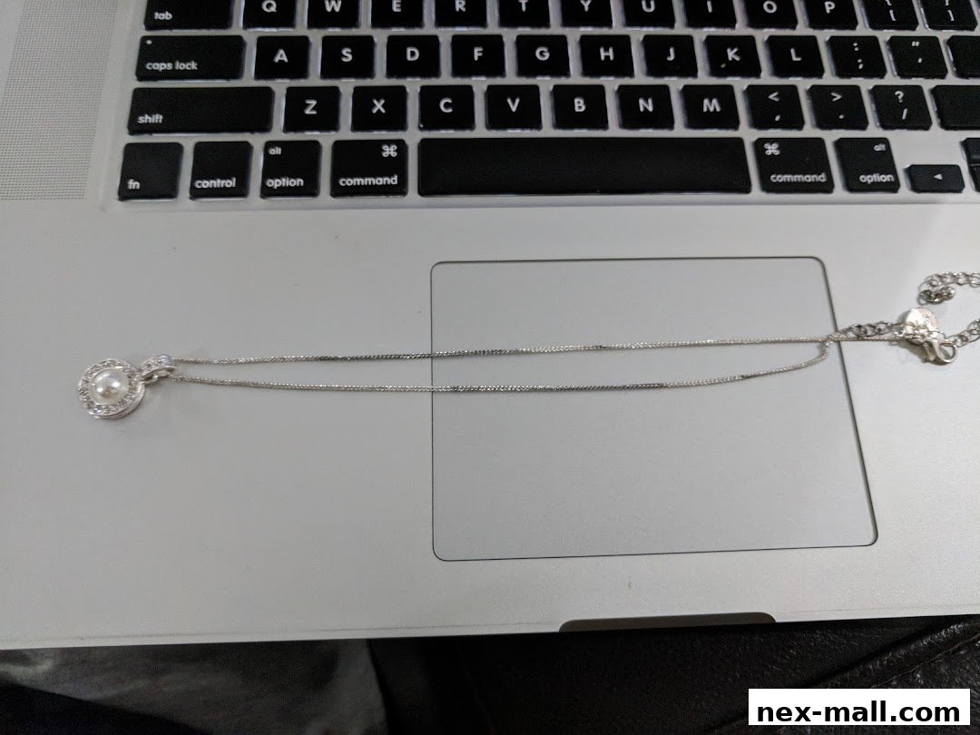 A pearl and diamond pendant necklace rests on a laptop keyboard.
