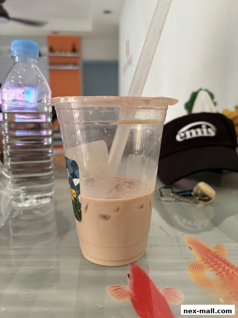 A close-up of a milky beverage with ice in a clear plastic cup, next to a bottle of water.