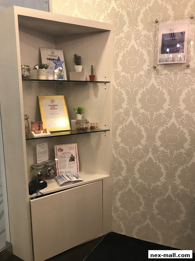 A display shelf with certificates, plants, and jars in a salon with patterned wallpaper.