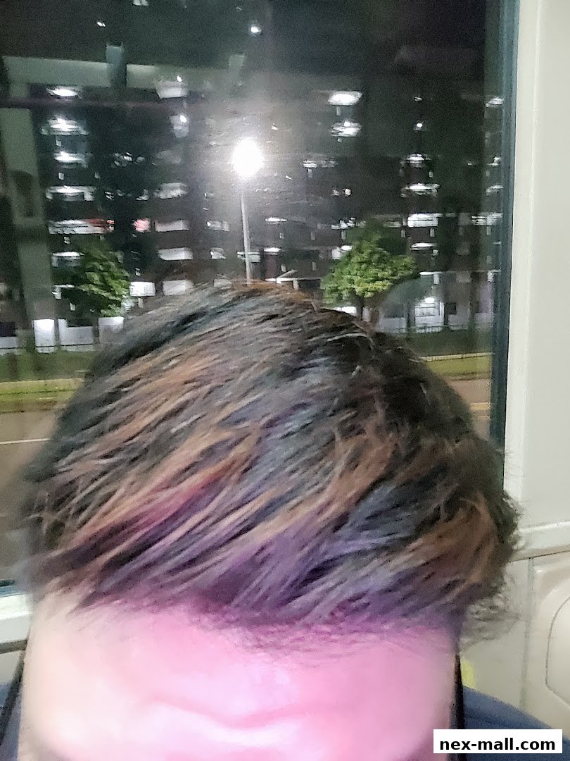 Close-up of a person's hair with highlights, viewed through a window at night.