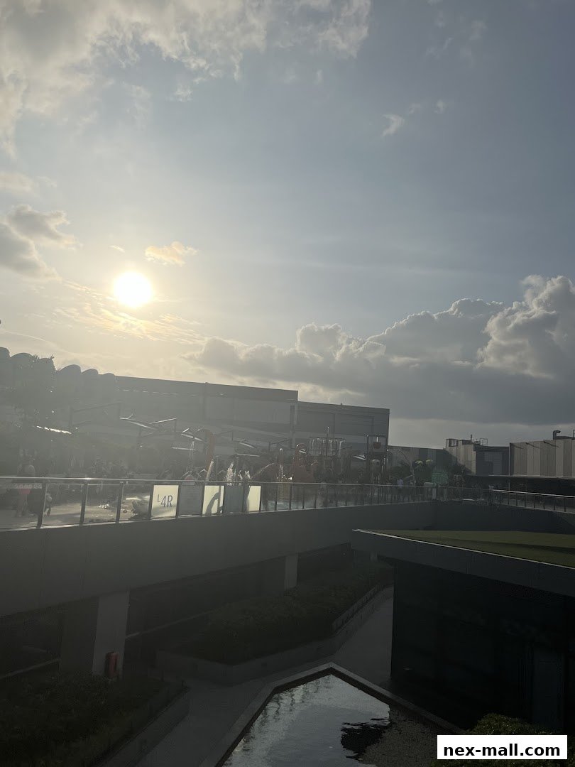 A bright sunny day with clouds over a modern building complex and a water feature.