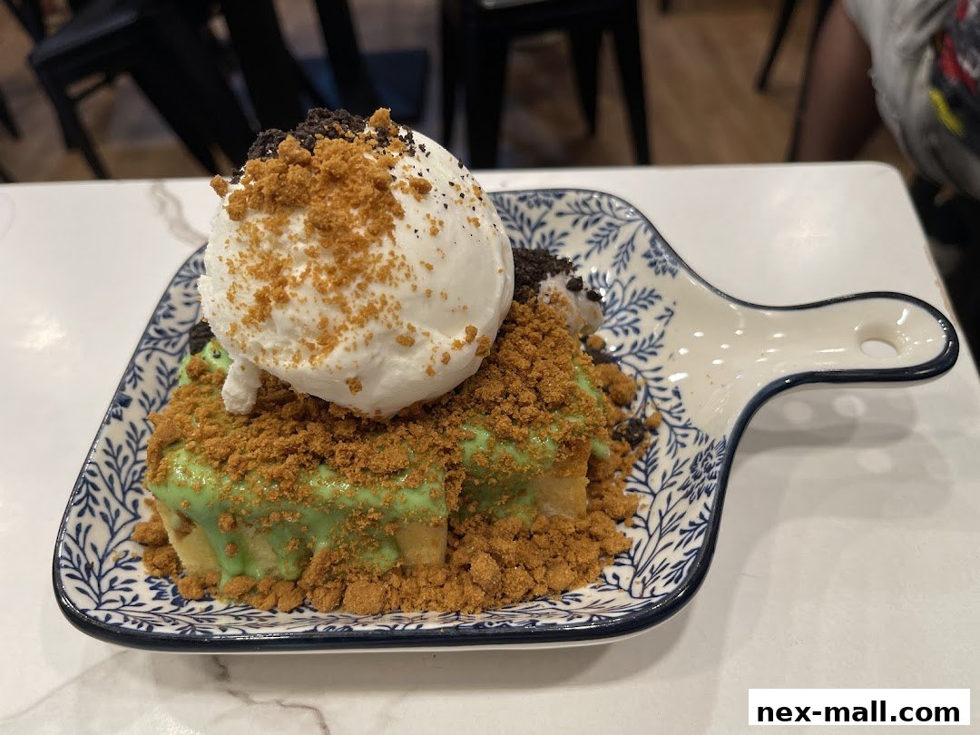 A delicious dessert with ice cream, crushed cookies, and green sauce on a decorative plate.