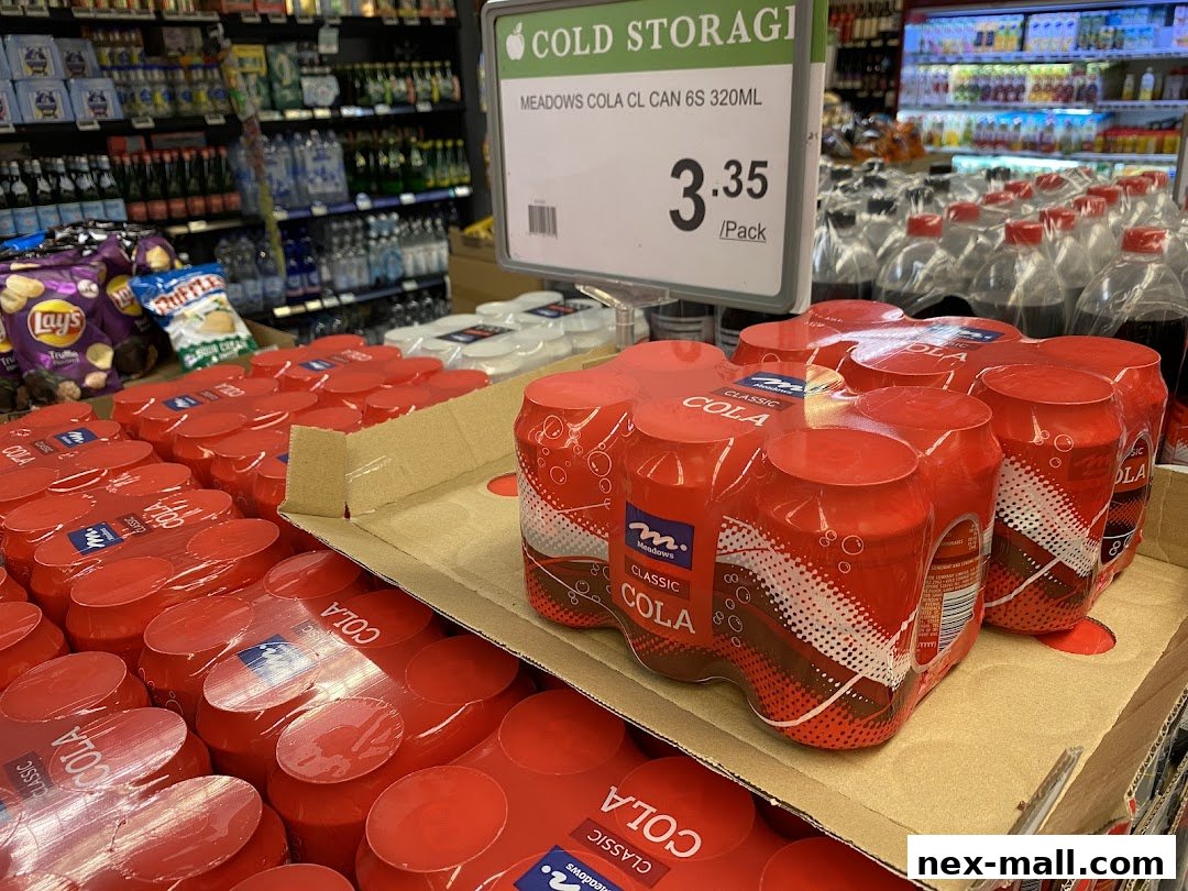 Packs of Meadows Classic Cola cans are displayed in a supermarket aisle.