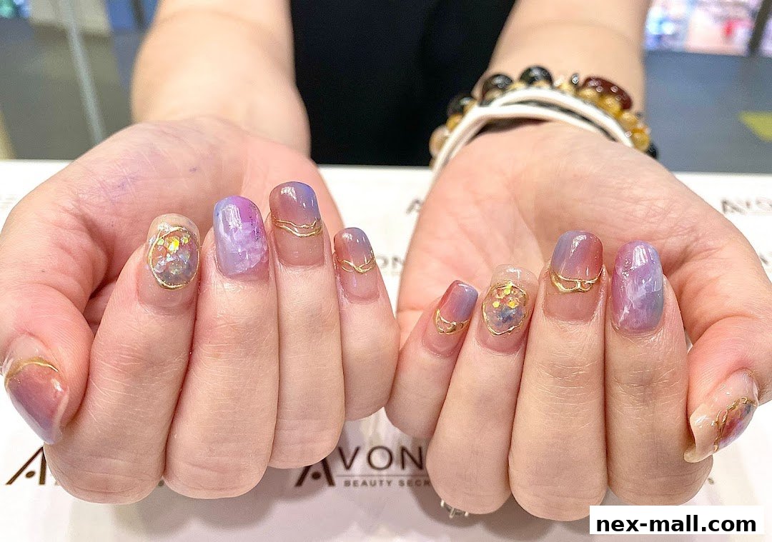 A close-up of hands showcasing beautifully designed nails with purple, pink, and gold accents.