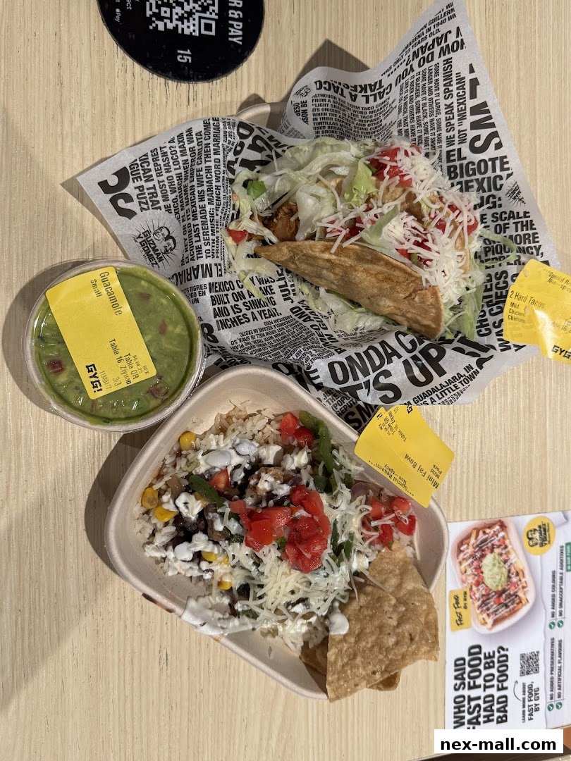 A table with Guzman y Gomez food including tacos, a rice bowl, and guacamole.