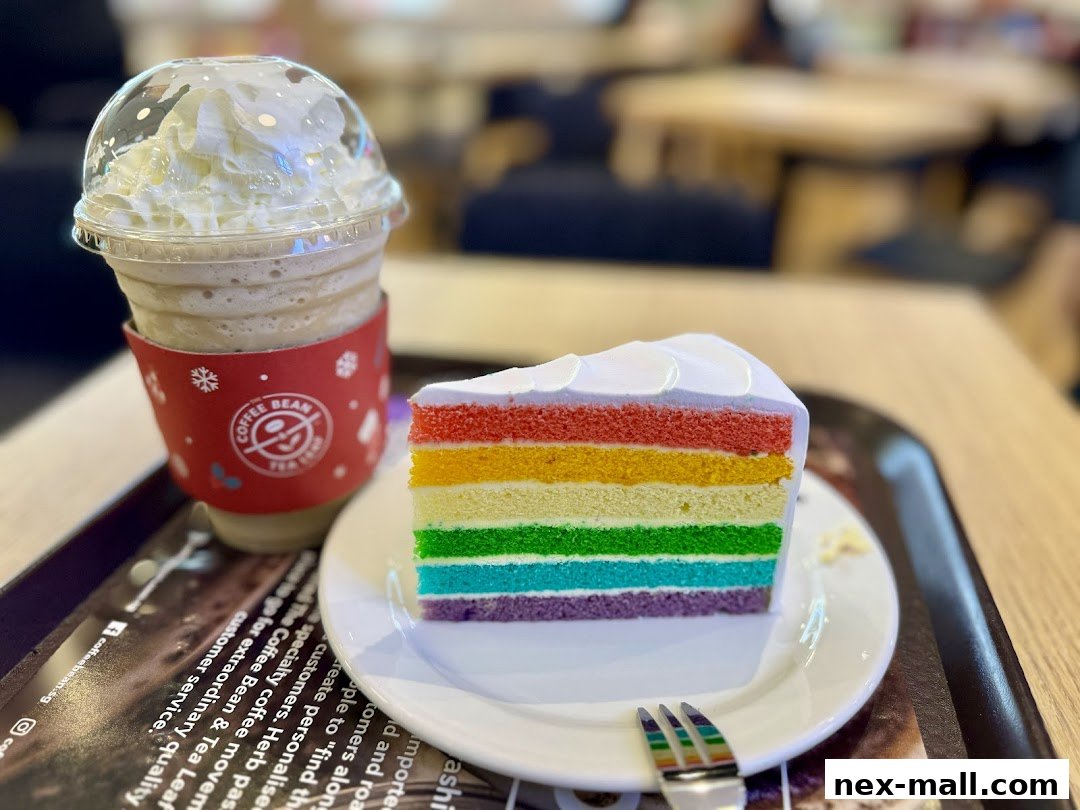 A slice of rainbow cake and a coffee drink with whipped cream.