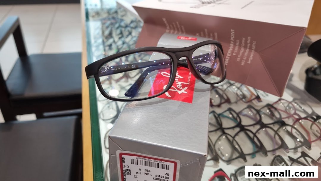 A pair of black Ray-Ban glasses displayed on a box with other eyeglasses in the background.