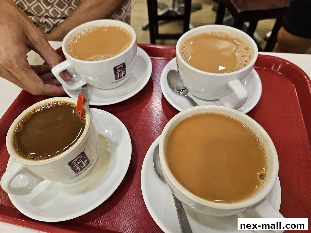Four cups of traditional Singaporean coffee and tea served on a red tray.
