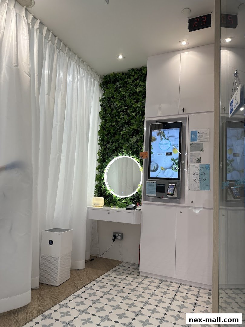 A modern beauty treatment room with a vanity, green wall, and digital screen.