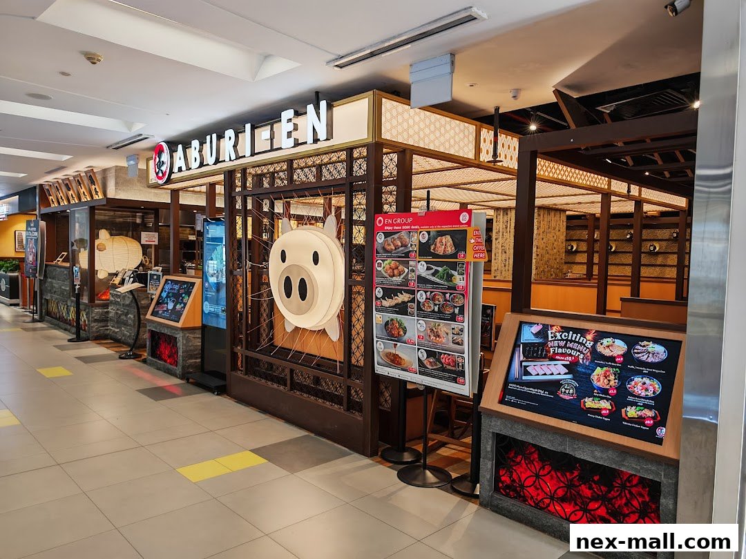The exterior of Aburi-EN Nex restaurant with a prominent pig mascot and menu displays.