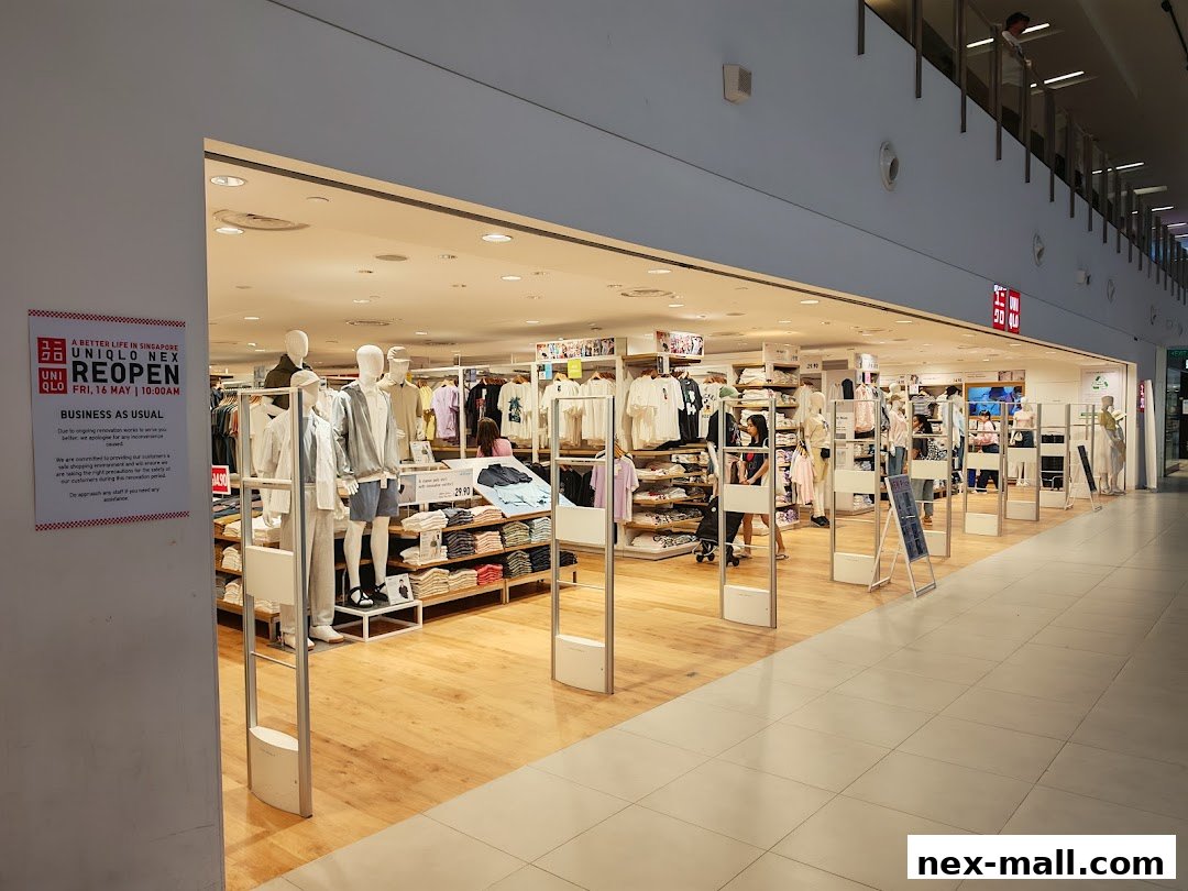 The entrance of a brightly lit Uniqlo store with mannequins displaying clothing and shelves of apparel.