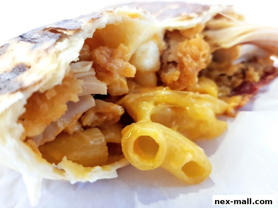 A close-up of a delicious wrap filled with macaroni and cheese and crispy chicken.