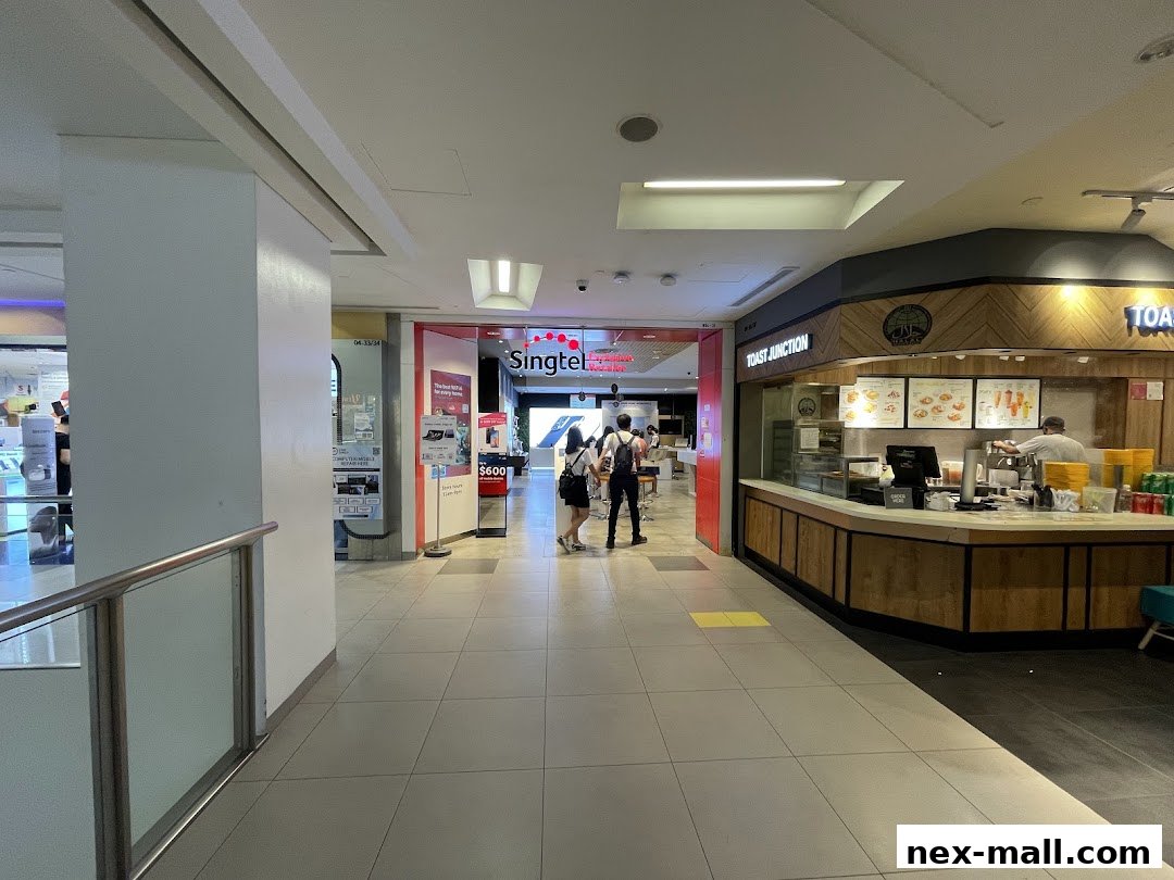 A view of a mall corridor with a Singtel store and a Toast Junction eatery.
