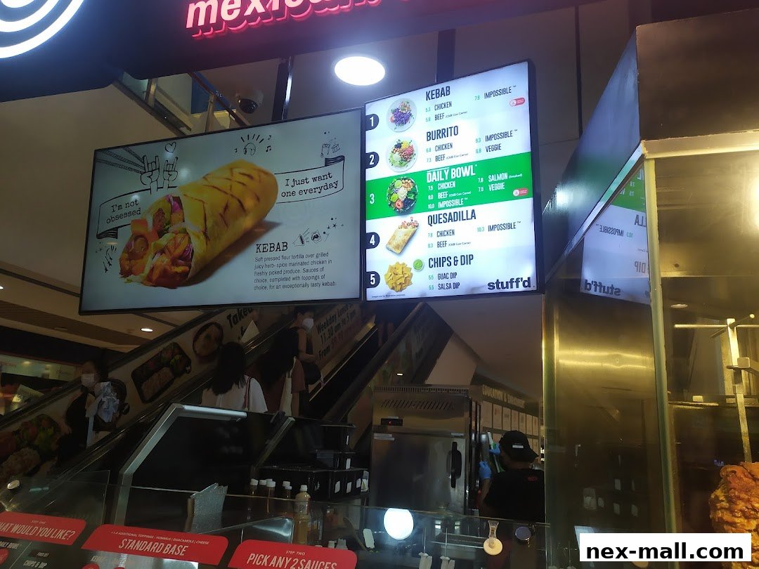 A digital menu board displays various kebab, burrito, and bowl options with prices.