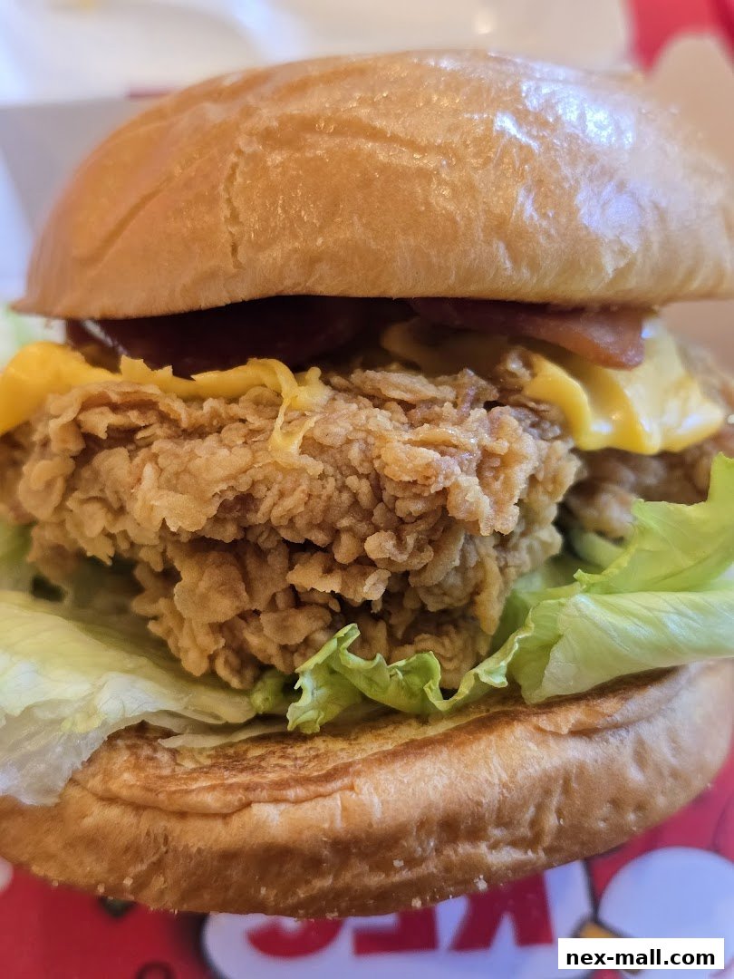 A close-up shot of a delicious KFC chicken burger with lettuce, cheese, and bacon.