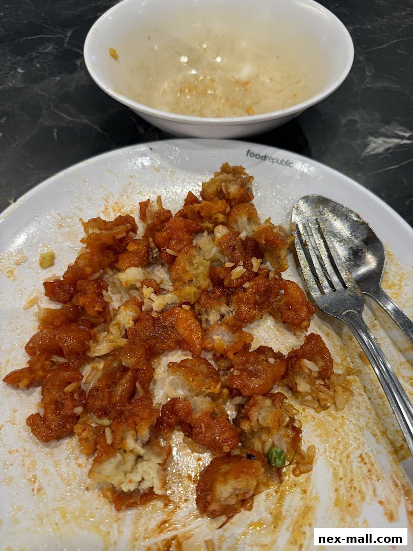 A plate of leftover fried chicken and rice with a spoon and fork.