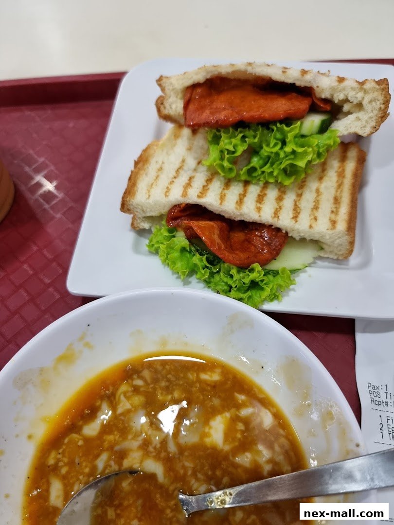 A close-up of a grilled sandwich and a bowl of soup with a receipt in the background.
