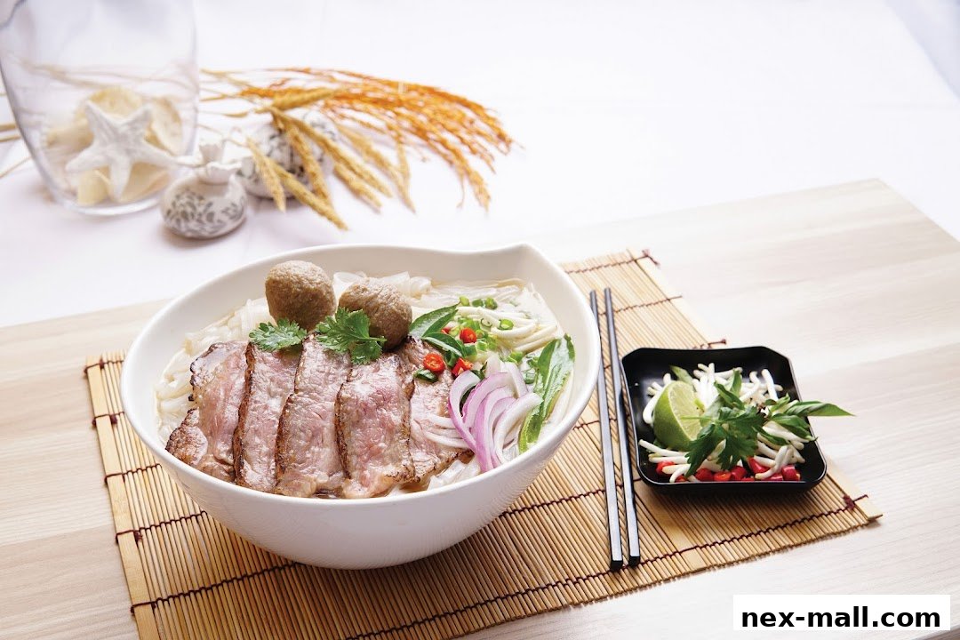 A steaming bowl of pho with thinly sliced beef, meatballs, and fresh herbs.