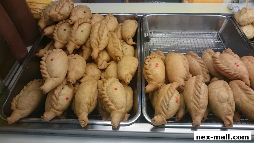 Two trays of golden-brown, freshly fried pastries, some with red or green dots.