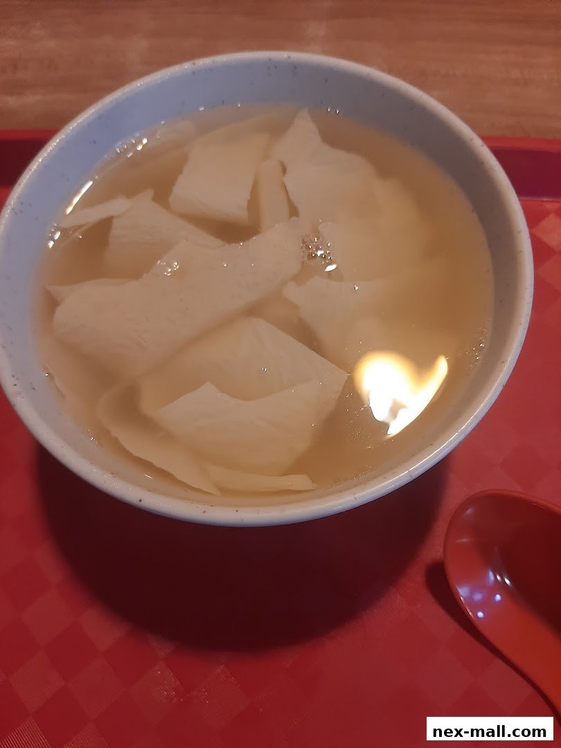 A close-up shot of a bowl of dessert with white pieces in a light-colored broth.