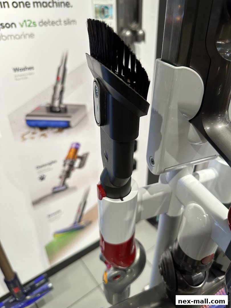 Close-up of a Dyson vacuum cleaner with various attachments and promotional material in the background.