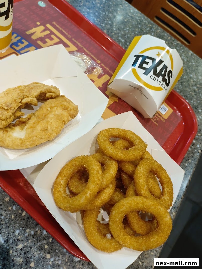 A tray of Texas Chicken food including crispy chicken tenders and onion rings.