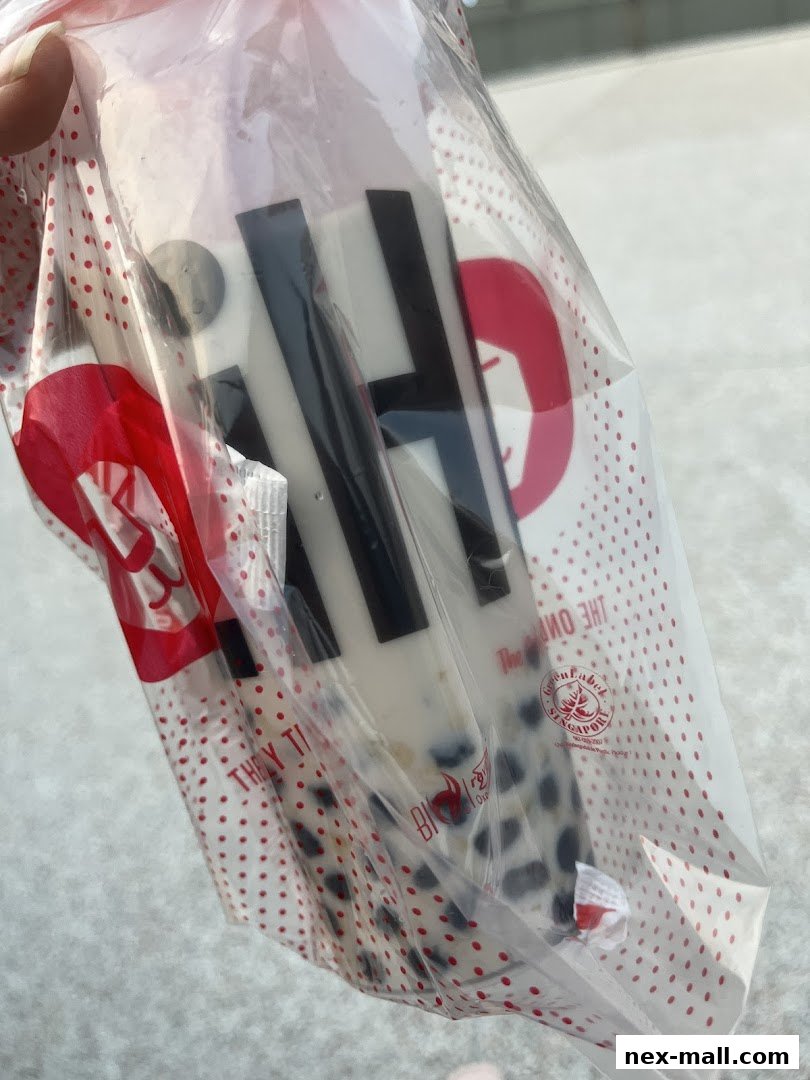 A person holds a plastic bag with a bubble tea drink from LiHO TEA.