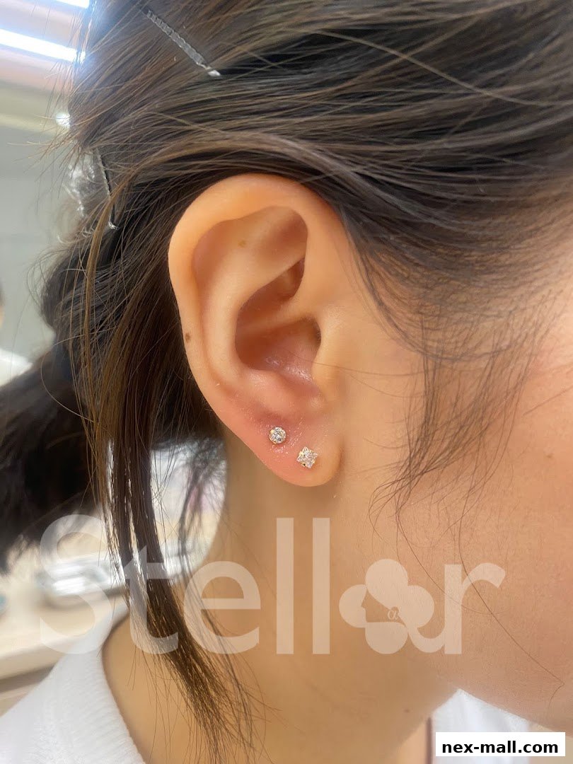 Close-up of a person's ear showcasing two delicate stud earrings.
