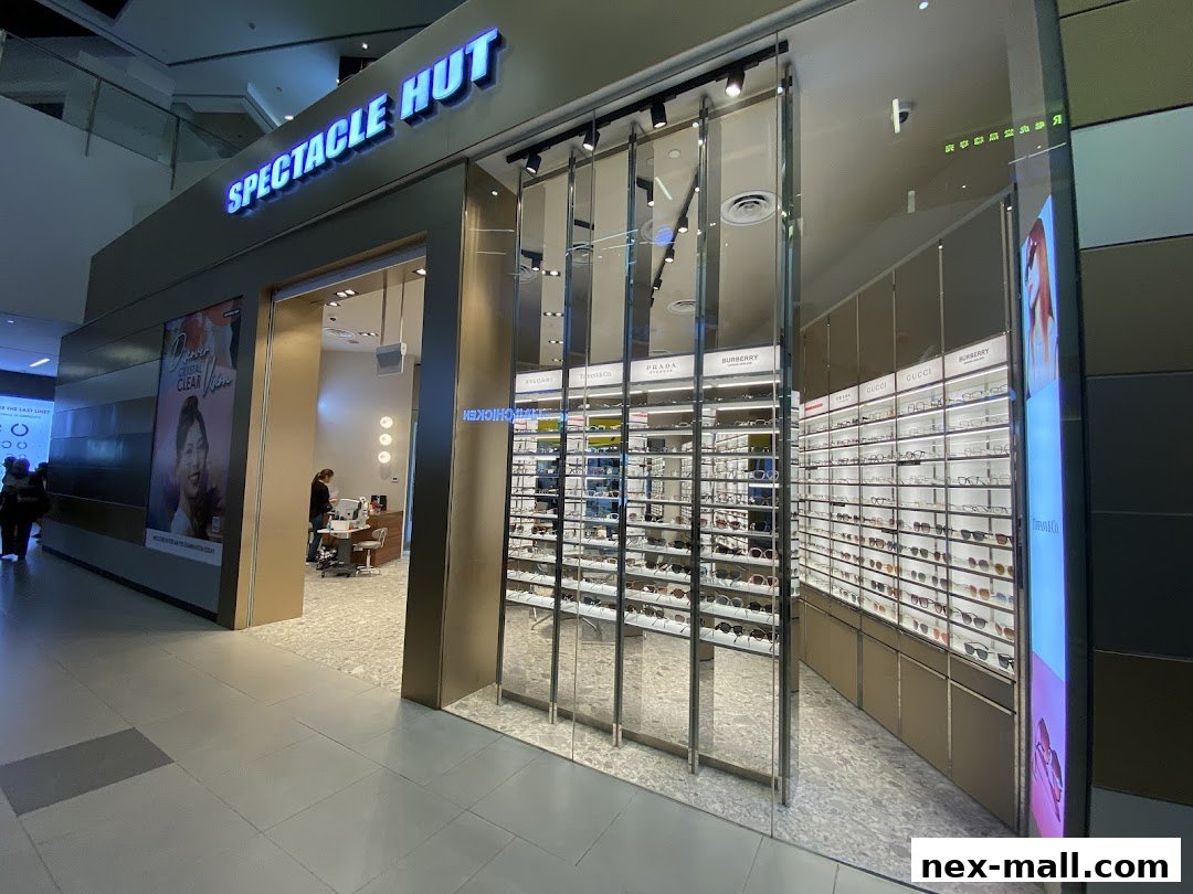 Spectacle Hut NEX shop front displaying a wide selection of eyewear and a poster.