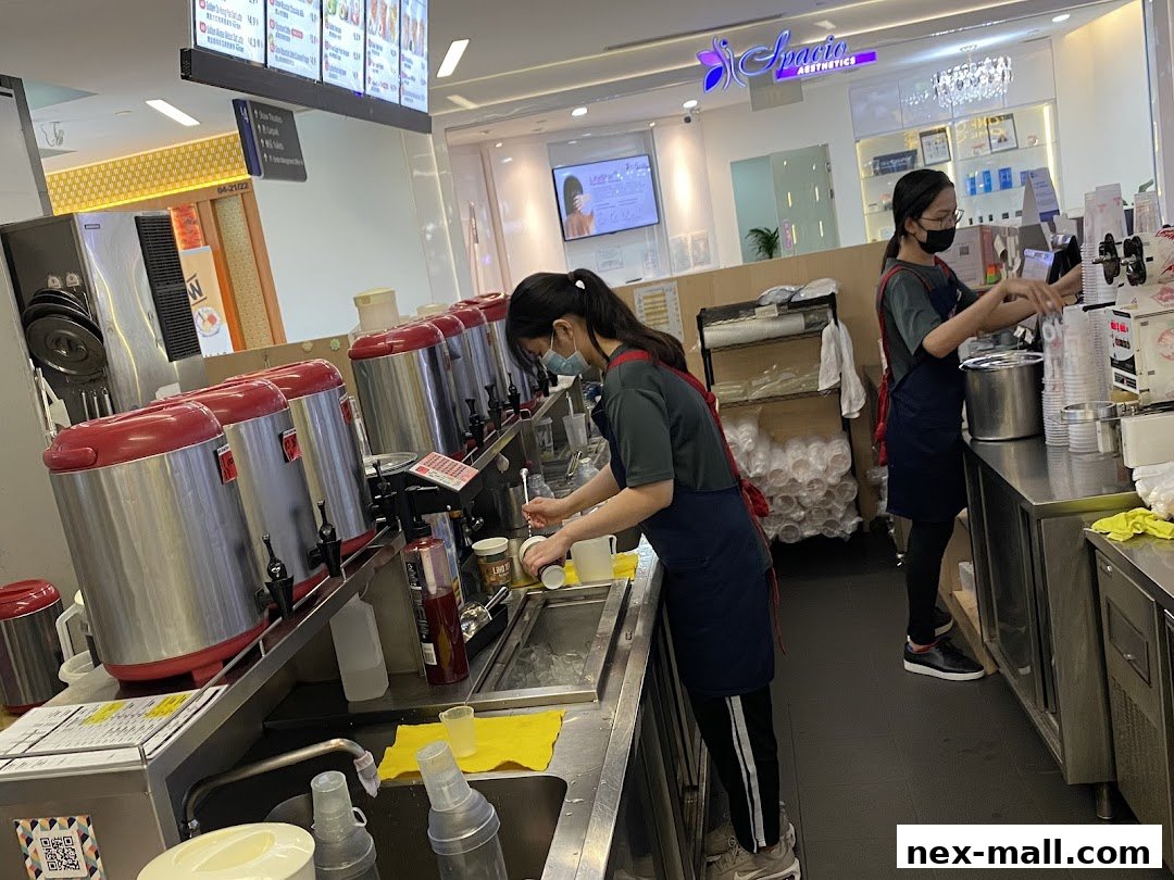 Two staff members preparing drinks behind a counter at a LiHO TEA outlet.