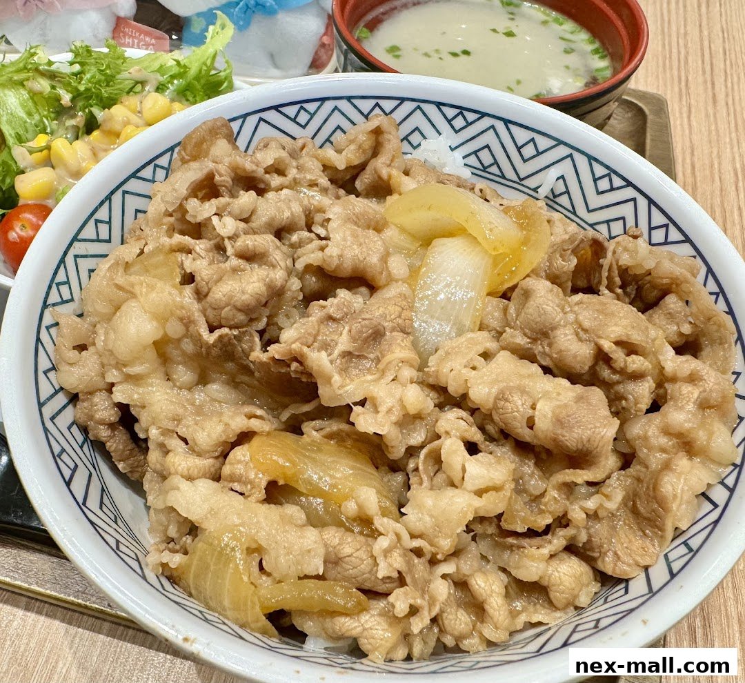 A close-up of a Yoshinoya beef bowl with a side salad and soup.