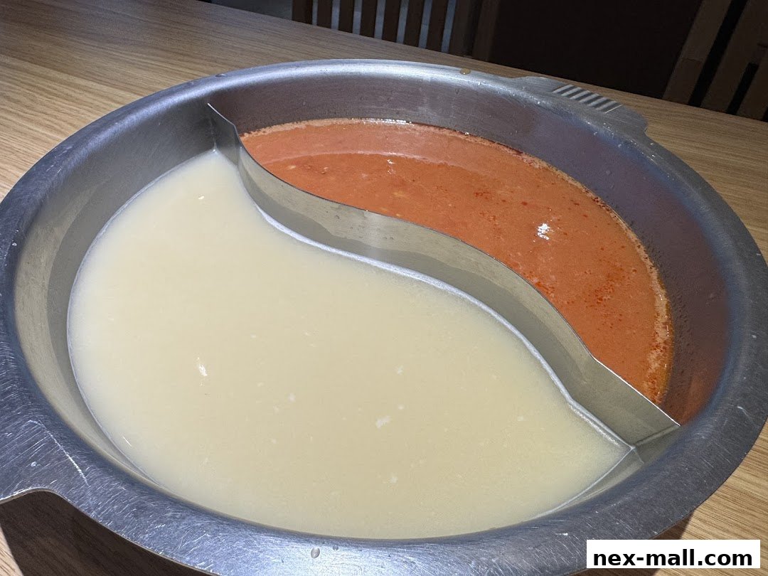 A split pot of broth, one creamy white and the other a reddish spicy soup.
