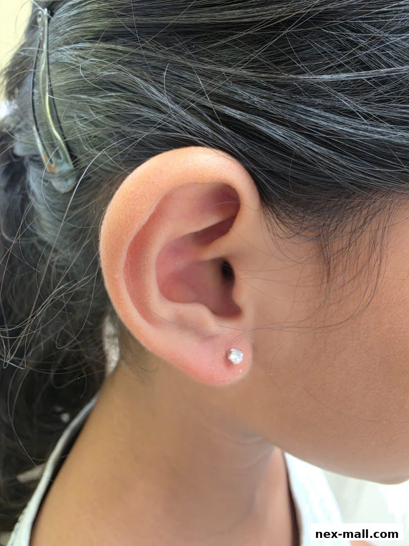 Close-up of a young person's ear with a small, sparkling stud earring.