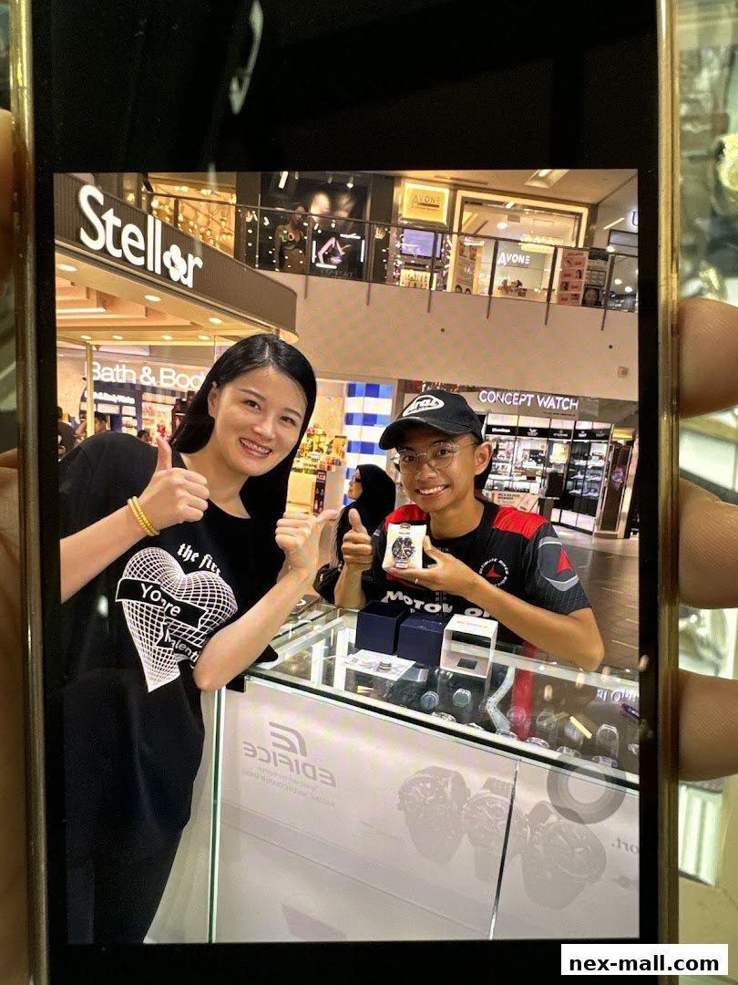 Two people giving thumbs up in front of a watch store display.