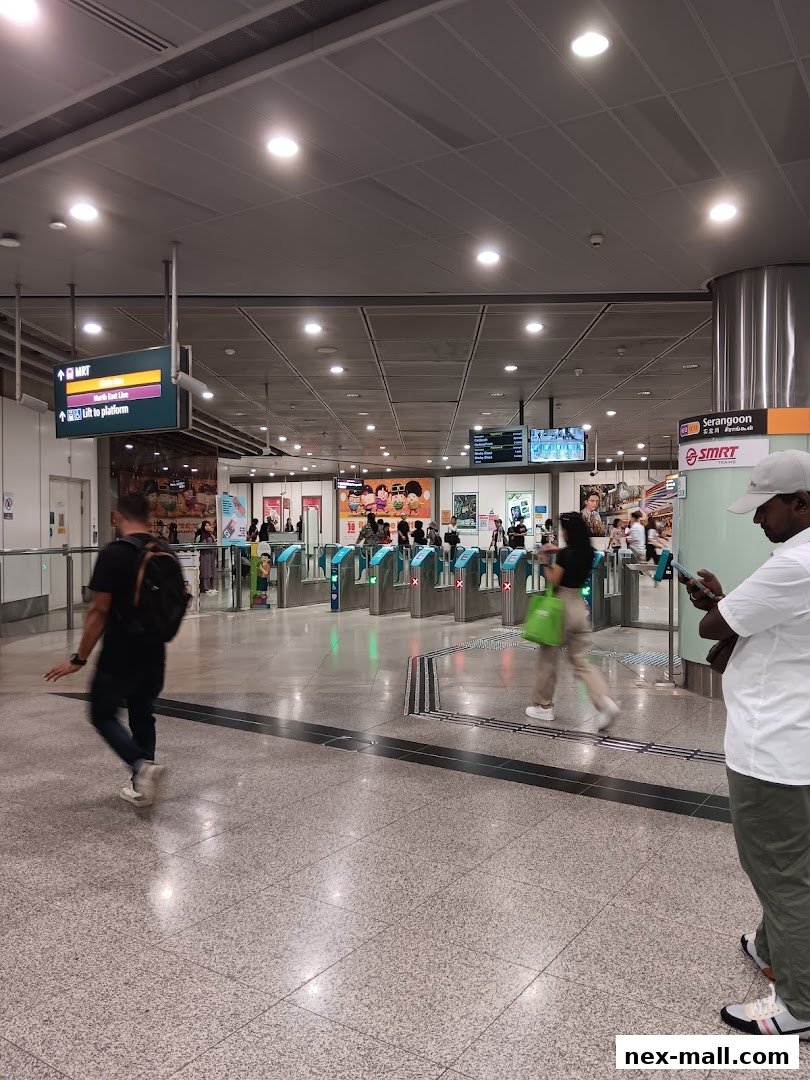 People passing through MRT station fare gates with directional signs overhead.
